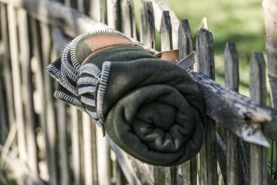 Petromax Wolldecke Schurwolle Grün Schwarz am Zaun hängend aufgerollt
